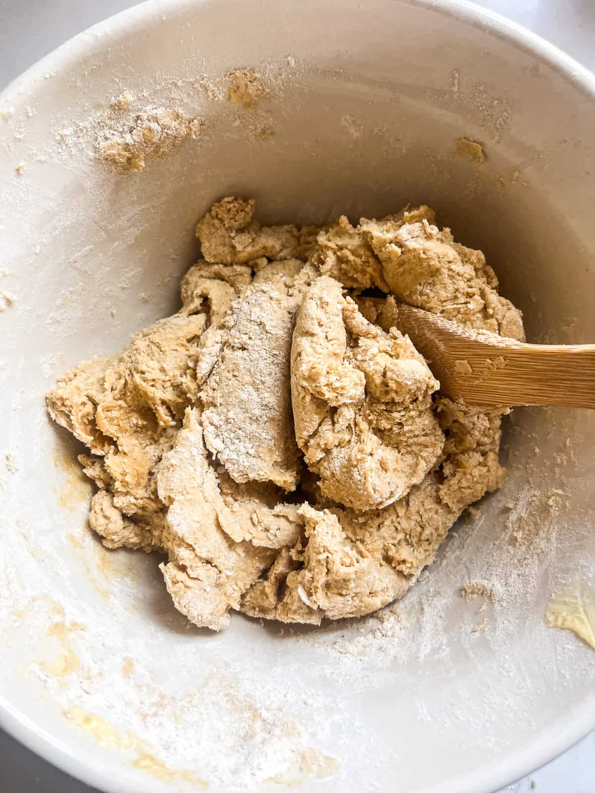 Stirring freshly milled tortilla dough in a mixing bowl.
