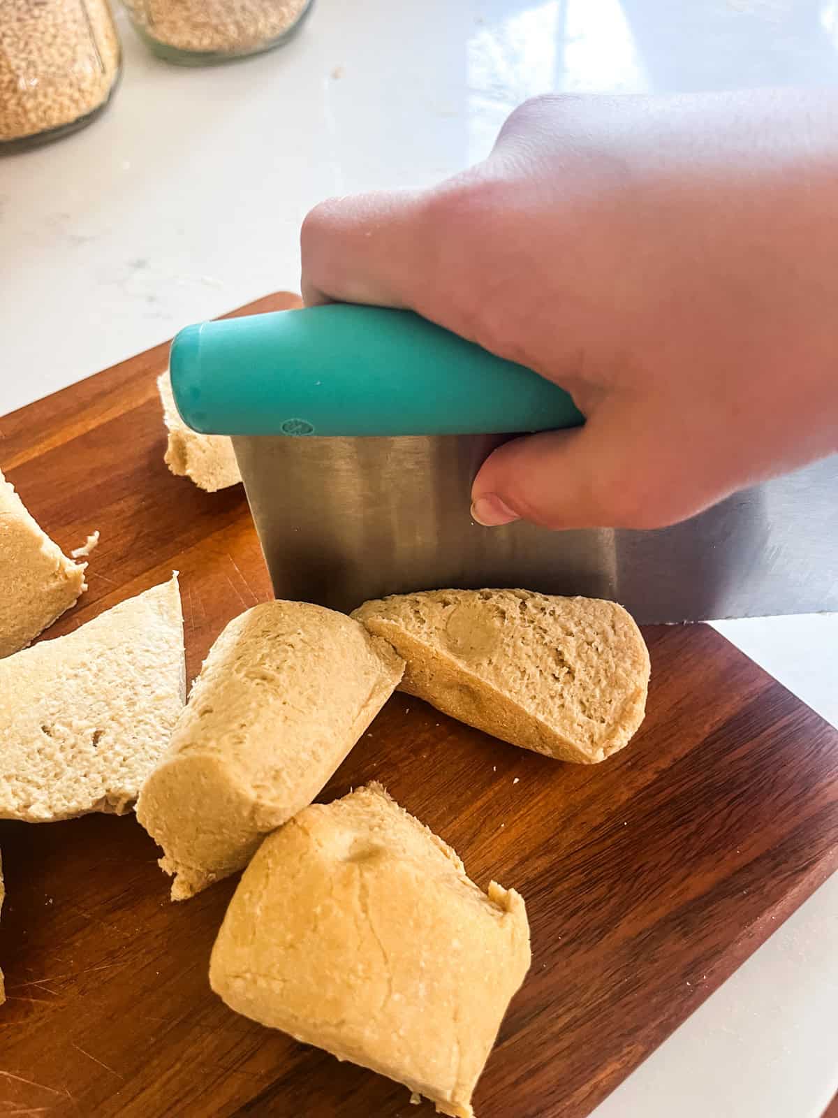 Cutting freshly milled tortilla dough with a dough cutter.