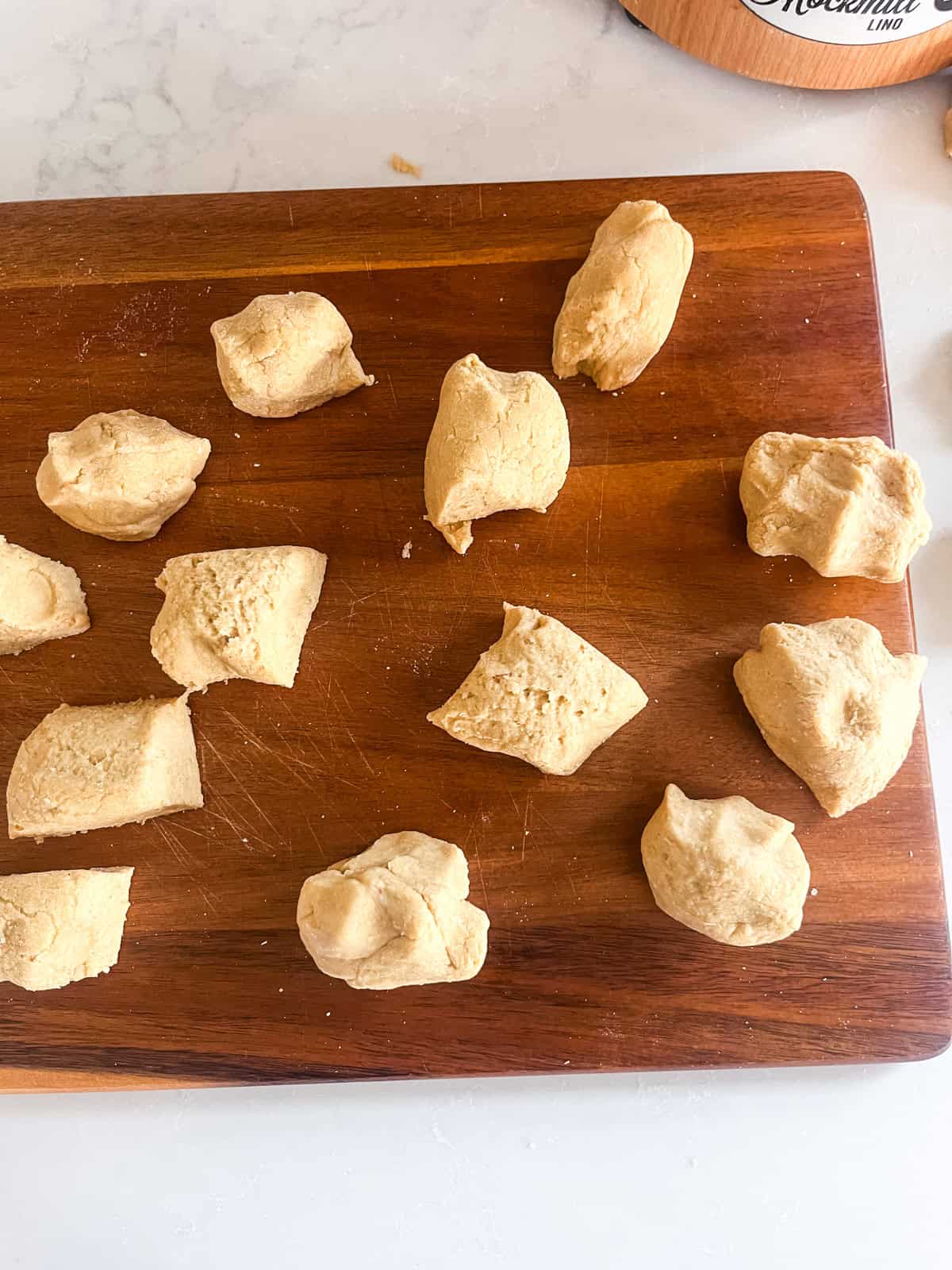 Balls of tortilla dough on a wooden cutting board.