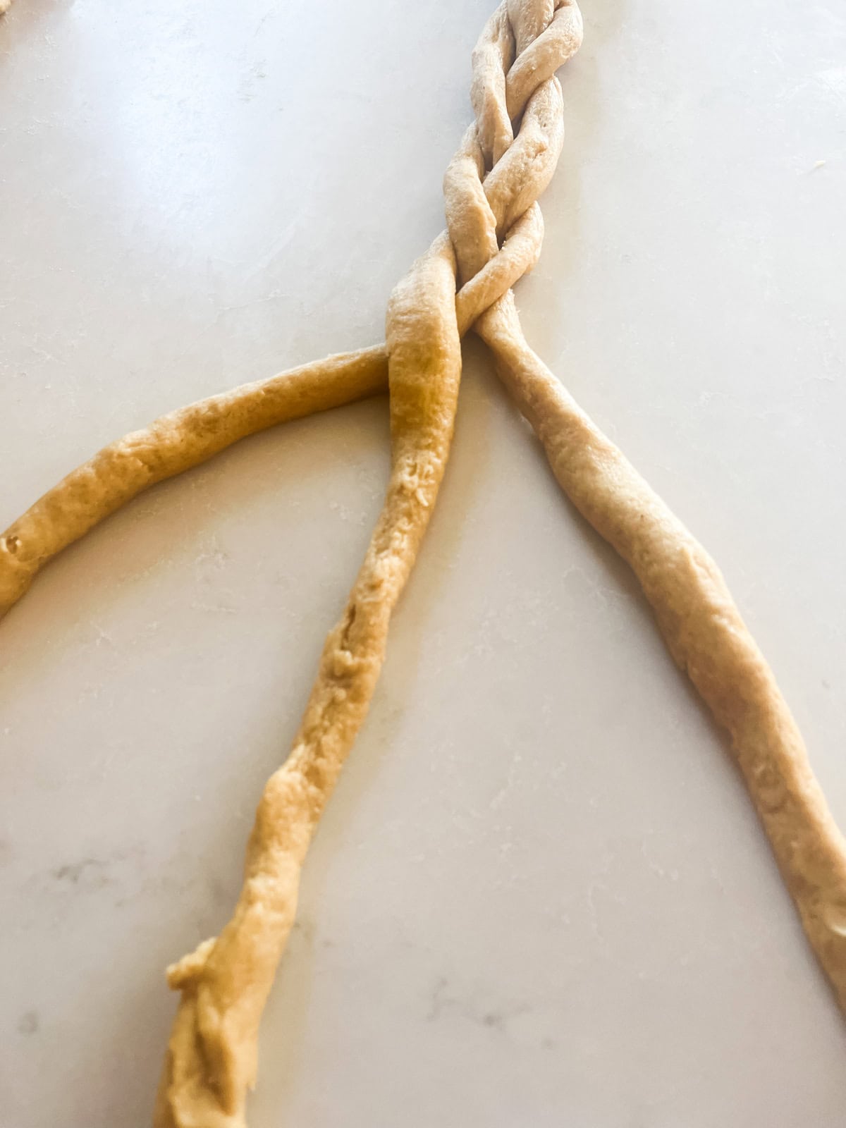 Braiding three ropes of donut dough.