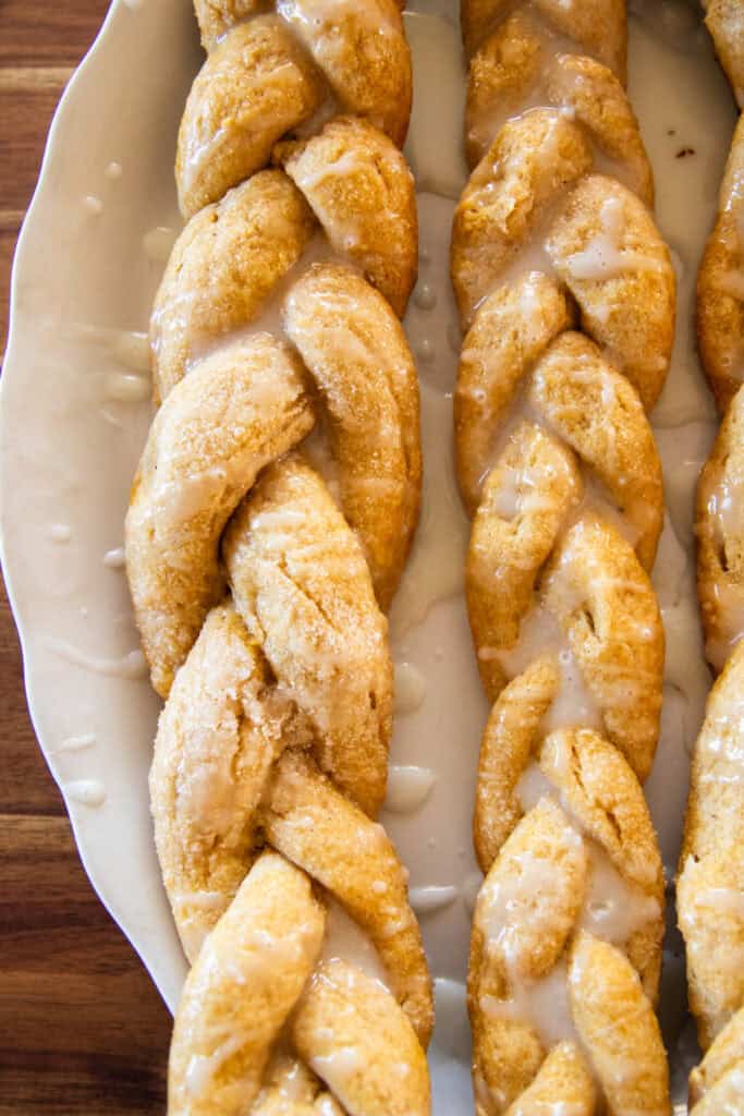 Long twisted donuts lined up on a white plate.