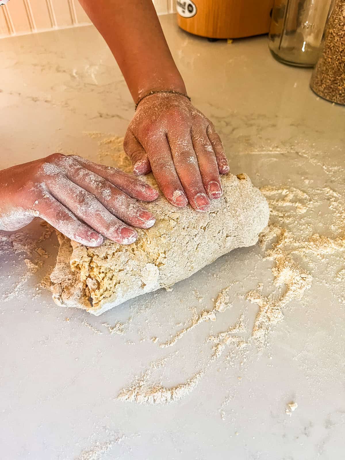 Kneading donut dough on a floured kitchen counter.