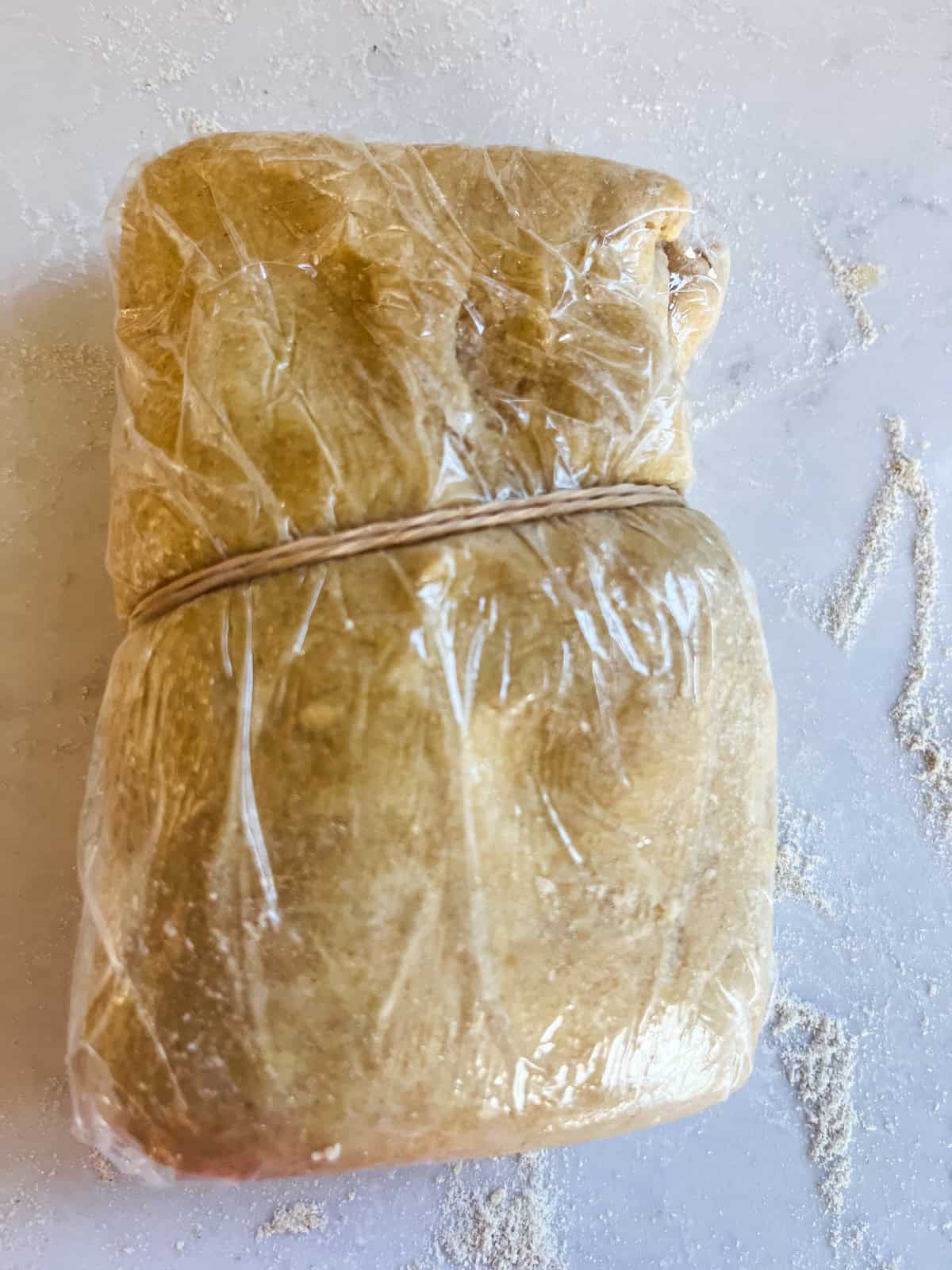 Freshly milled donut dough wrapped in plastic wrap.