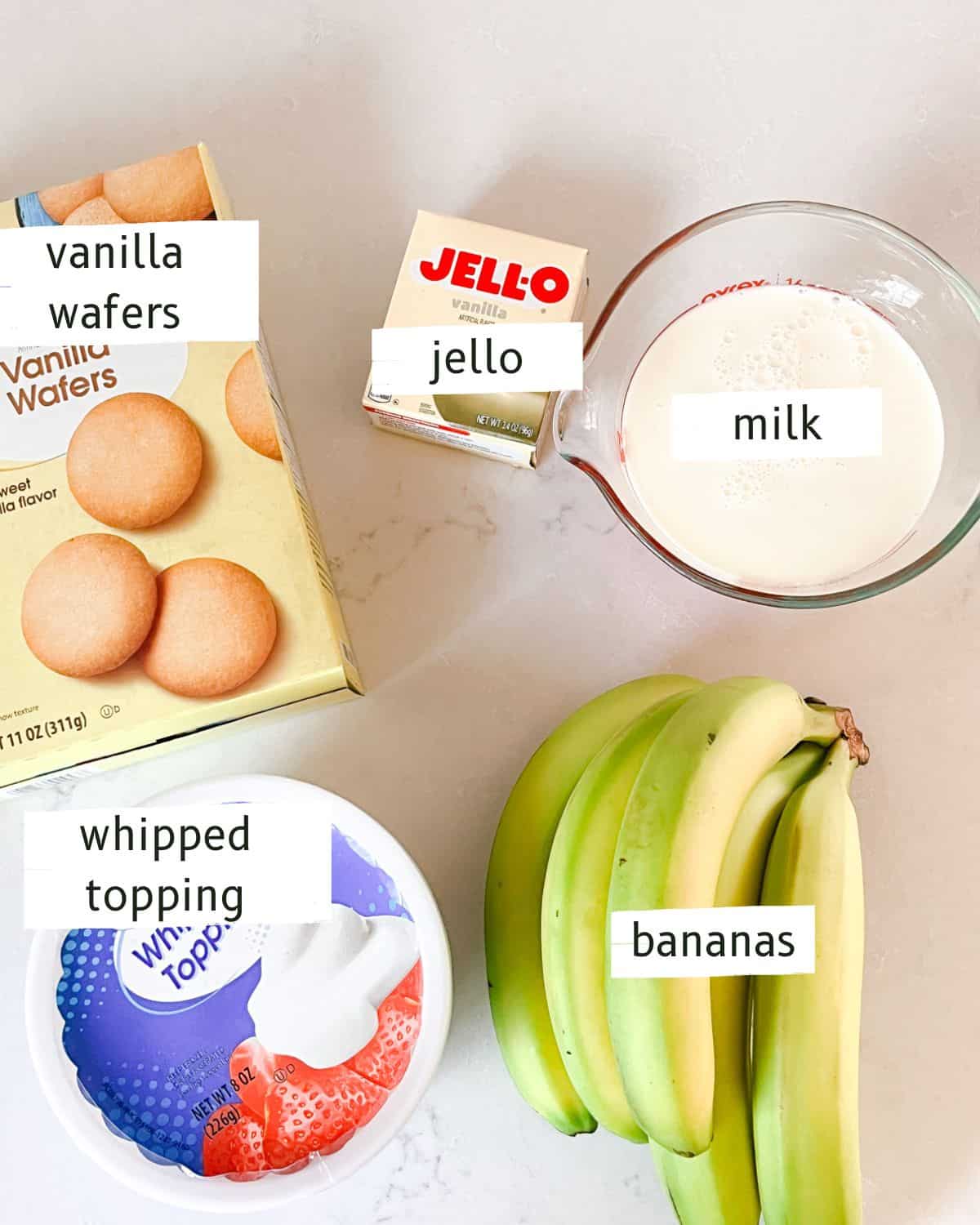 Homemade banana pudding ingredients labeled on a white backdrop.