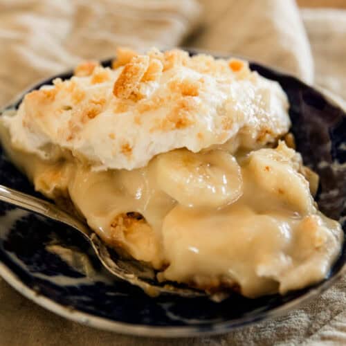 A serving of banana pudding in a blue bowl with a spoon.
