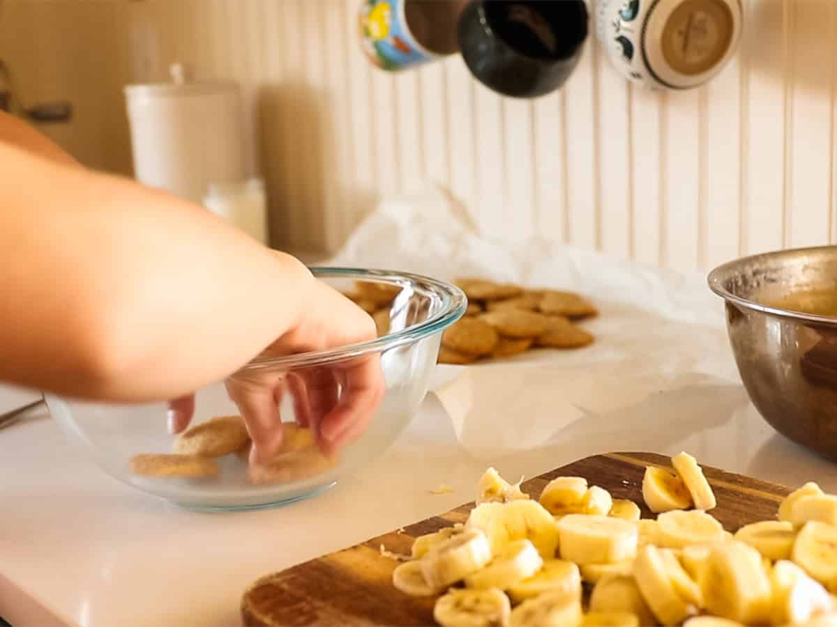 Layering banana slices in a glass bowl.