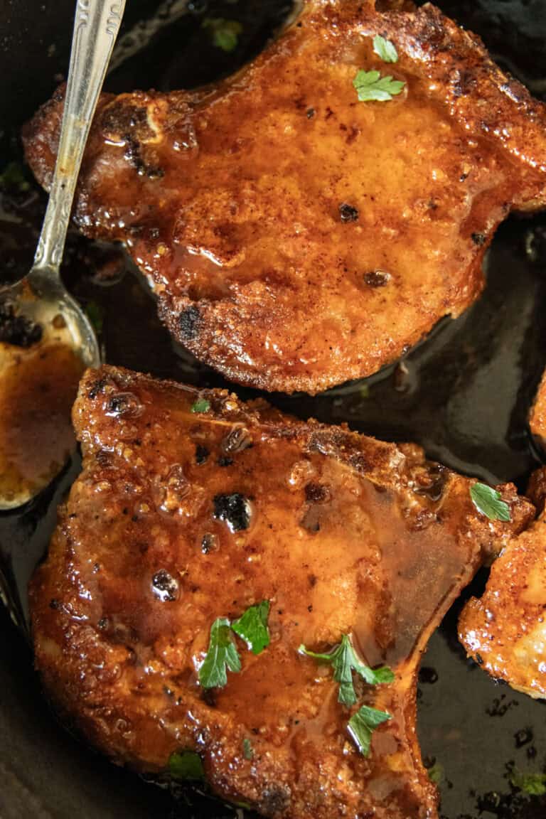 Pan-fried pork chops in a cast iron skillet.