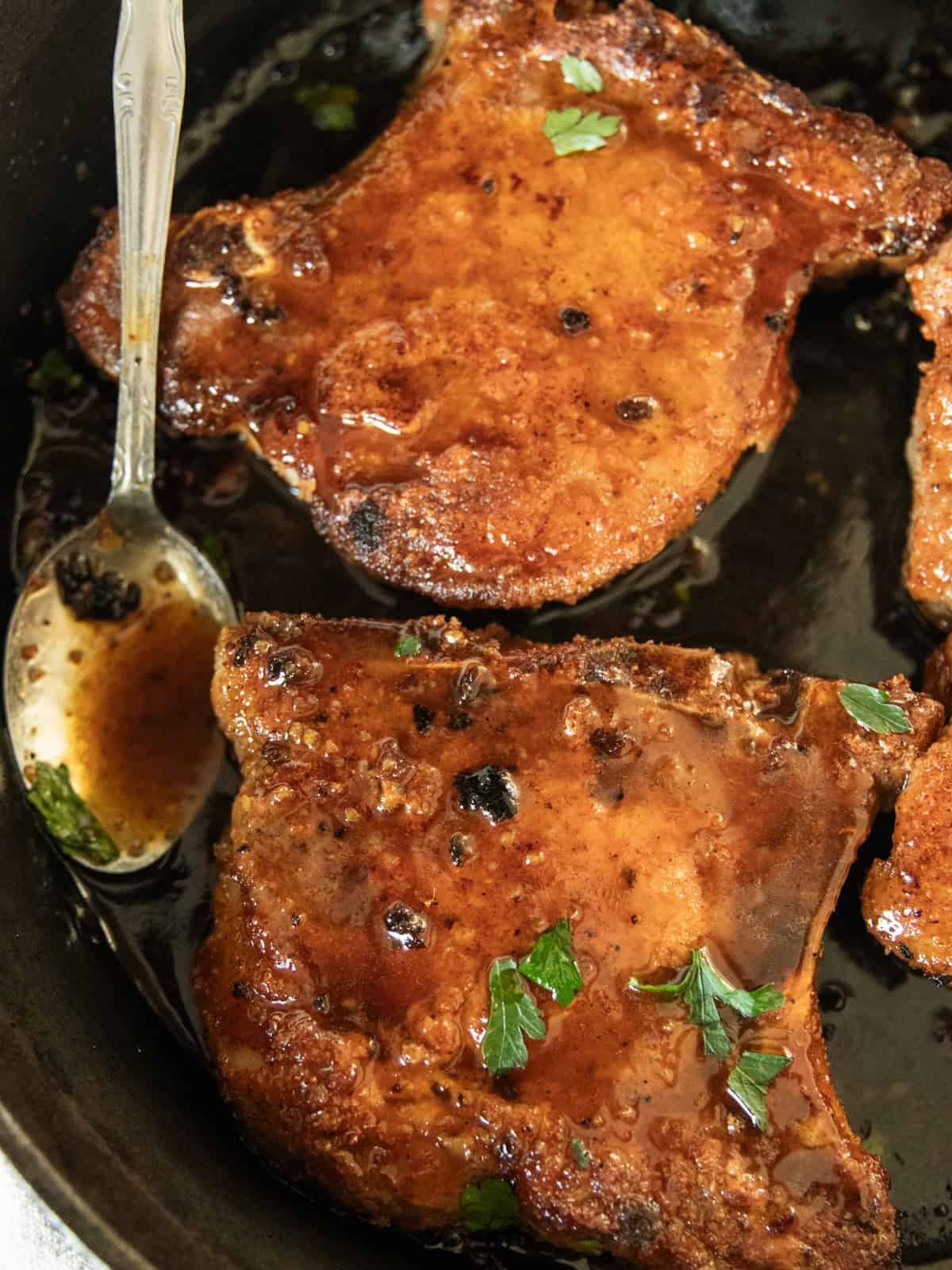 Pan-fried pork chops in a cast iron skillet.