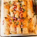 A pan of venison enchiladas with a jar of salsa on the side.