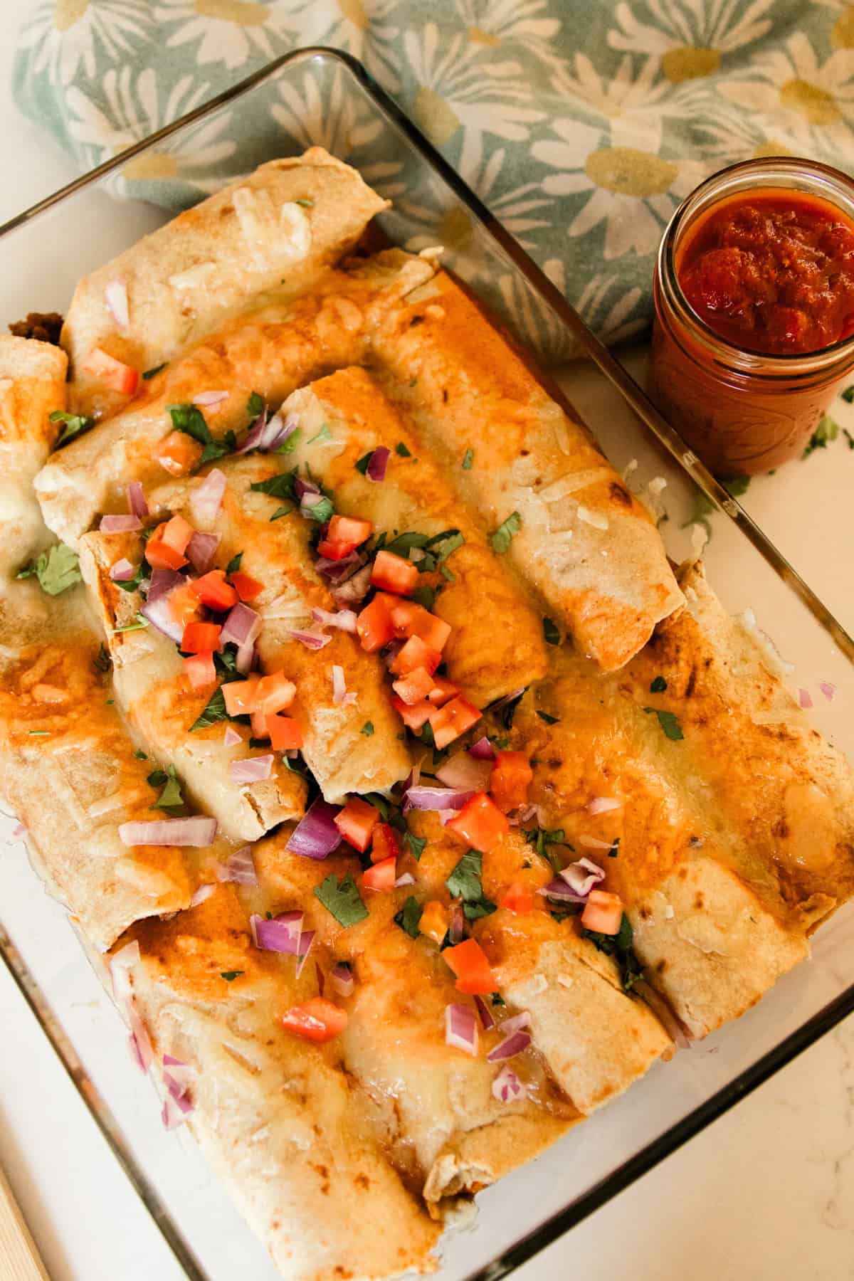 Venison enchiladas in a glass baking dish with salsa on the side.