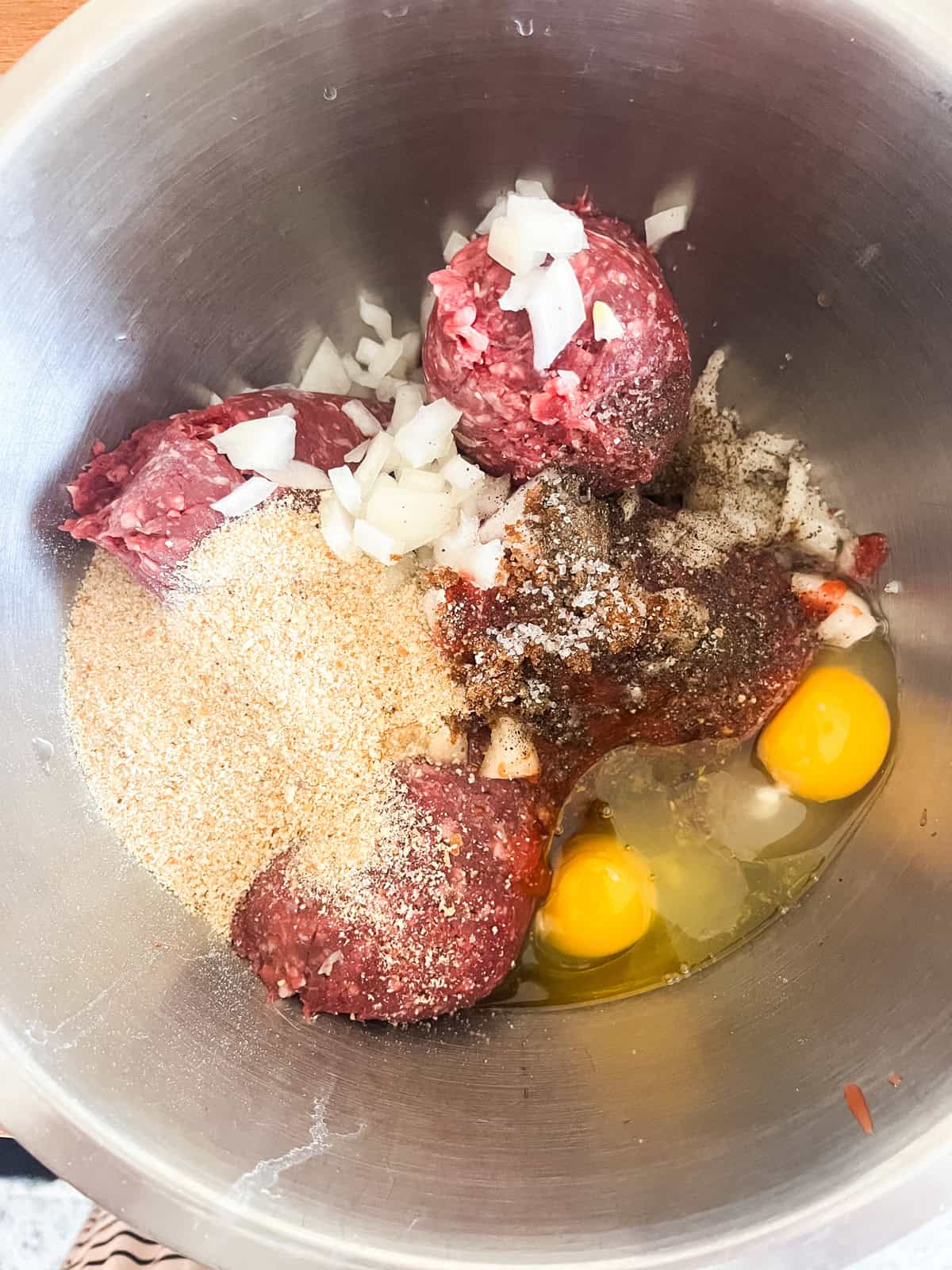 Mixing the ground venison mixture in a metal bowl.
