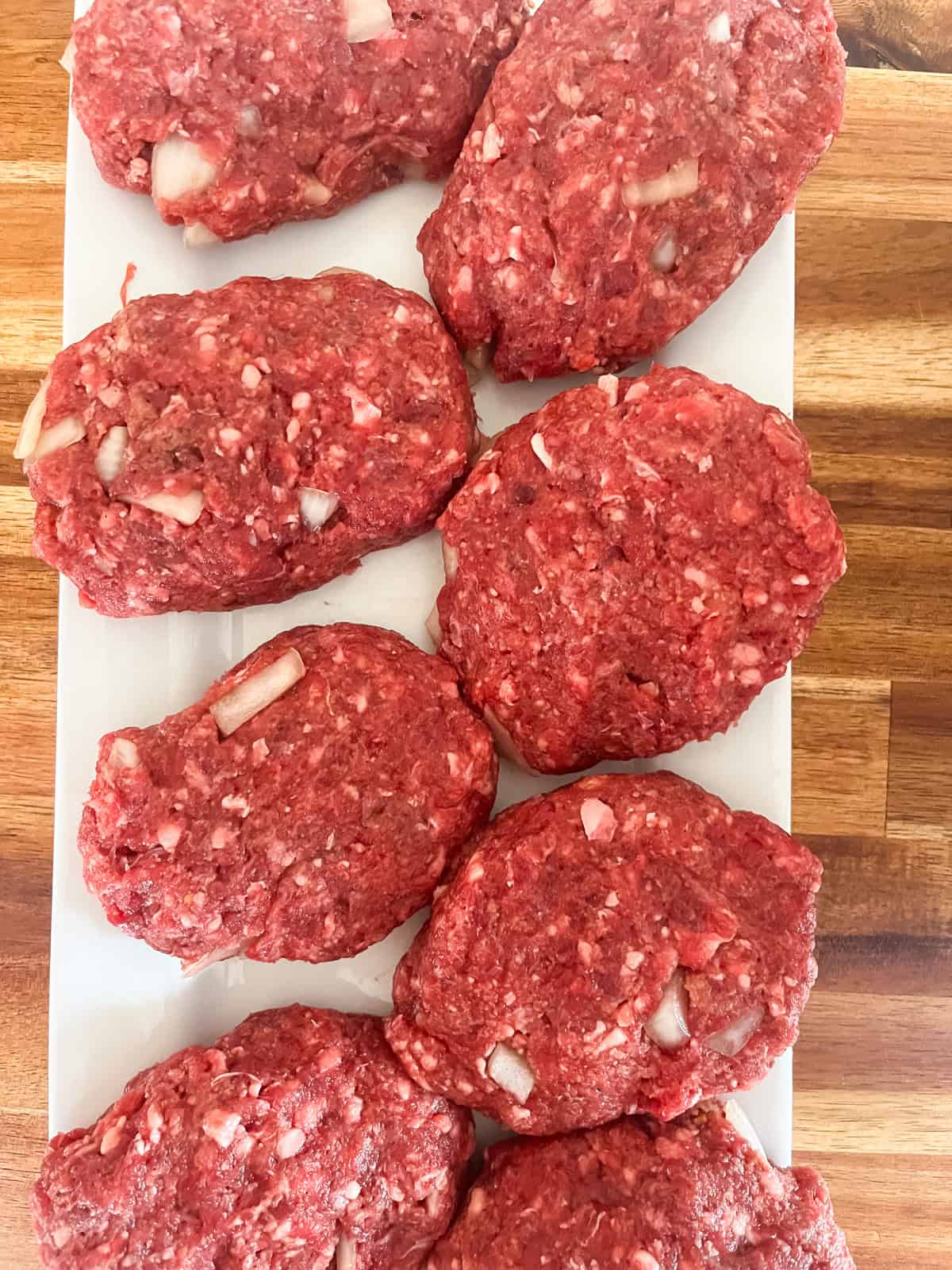 Raw Salisbury steak patties shaped on a tray.