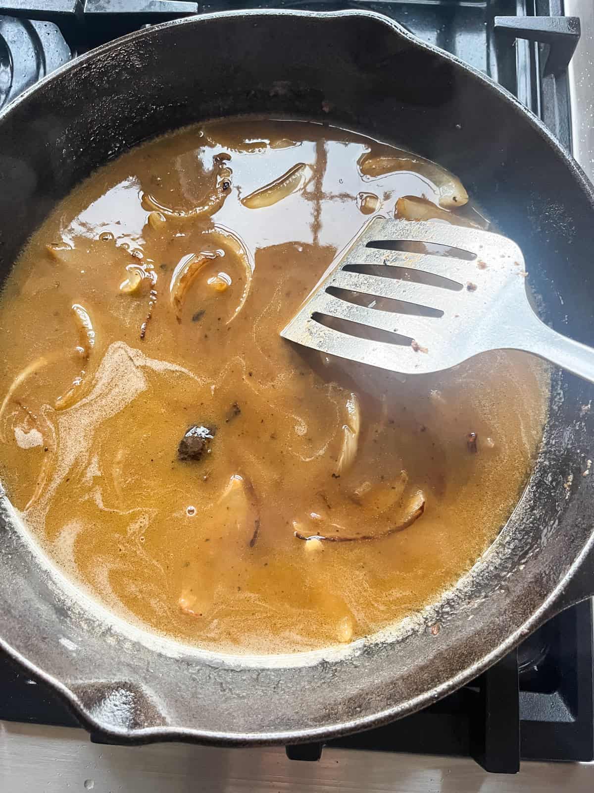 Salisbury steak gravy unthickened in a skillet.