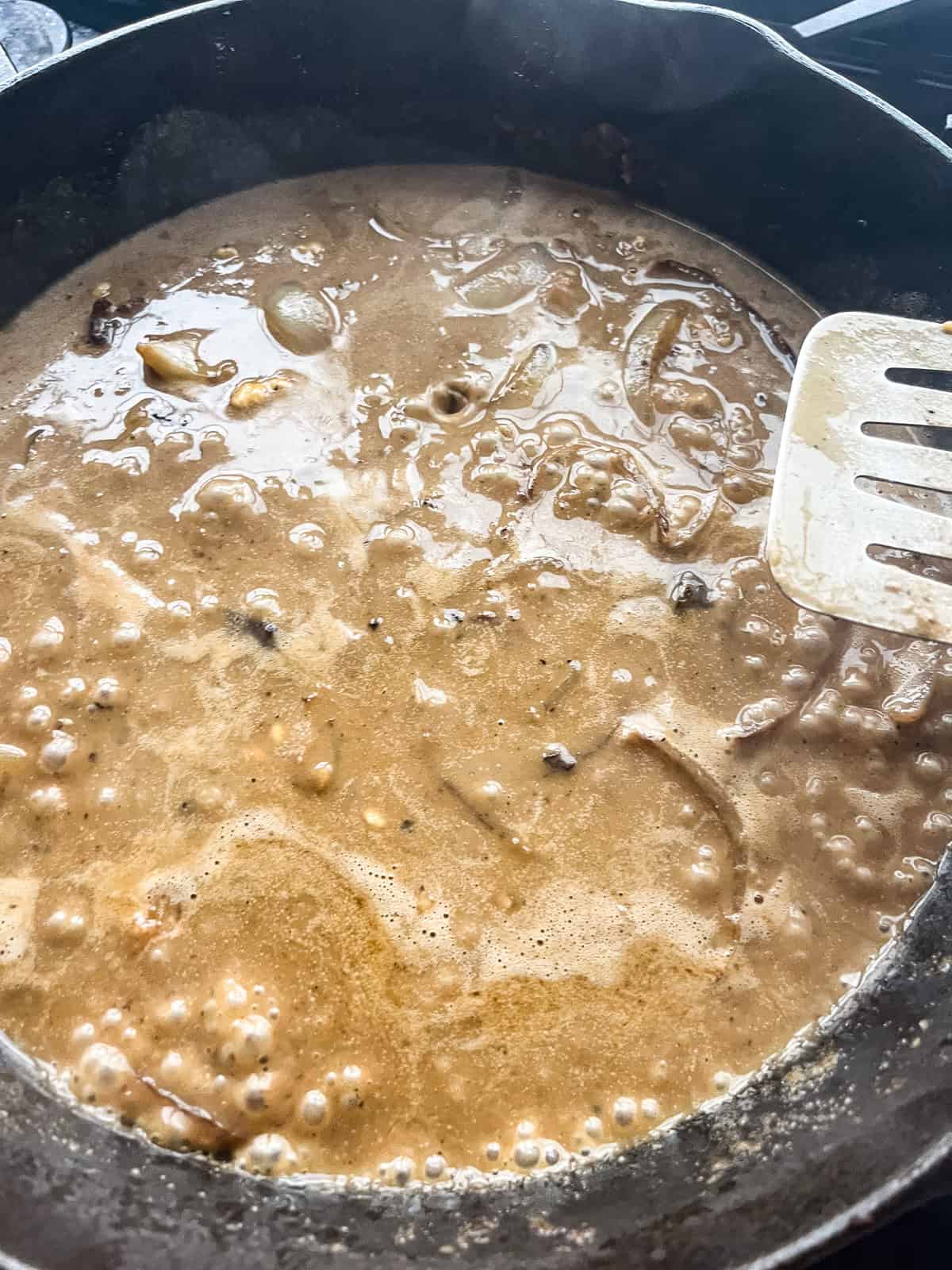 Salisbury steak gravy simmering in a cast iron skillet.