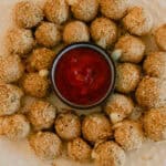 Whole wheat mozzarella cheese balls on a white serving plate with marinara sauce in a bowl in the middle.