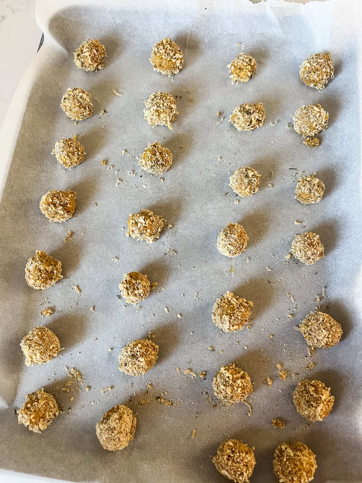A sheet pan with whole wheat mozzarella cheese balls lined up, ready to be baked.