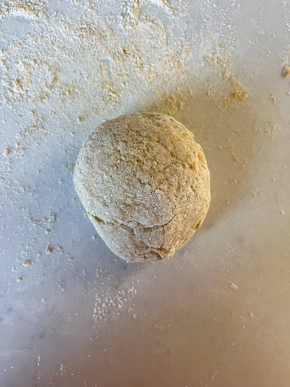 A ball of dough sitting on a floured surface.