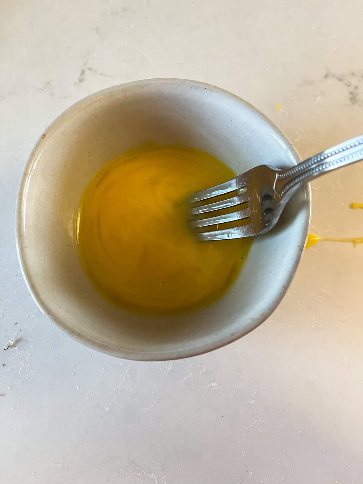 Whisking egg and milk together with a fork.
