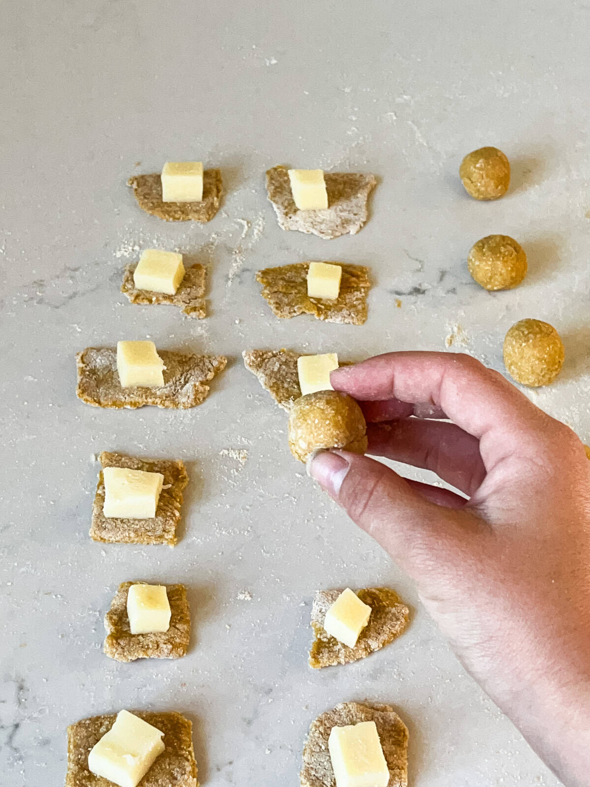 Rolling cheese cubes into pieces of raw dough.