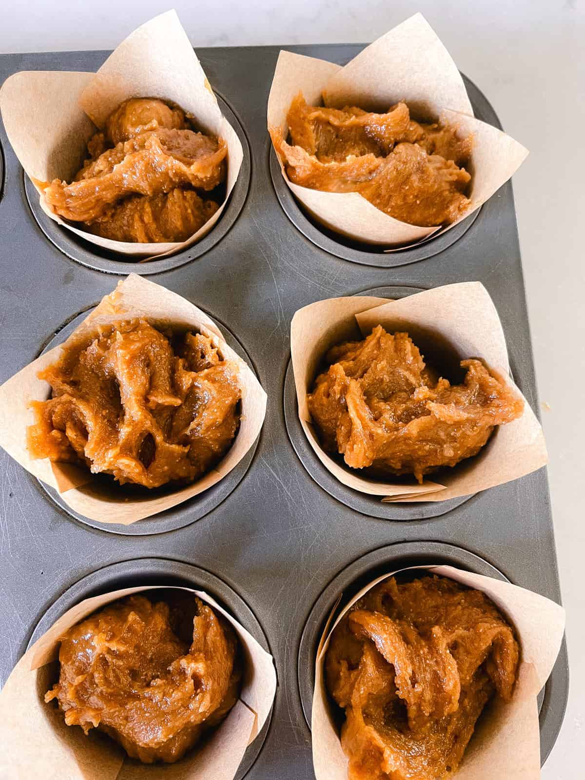Peanut butter muffin batter in paper muffin tin liners.