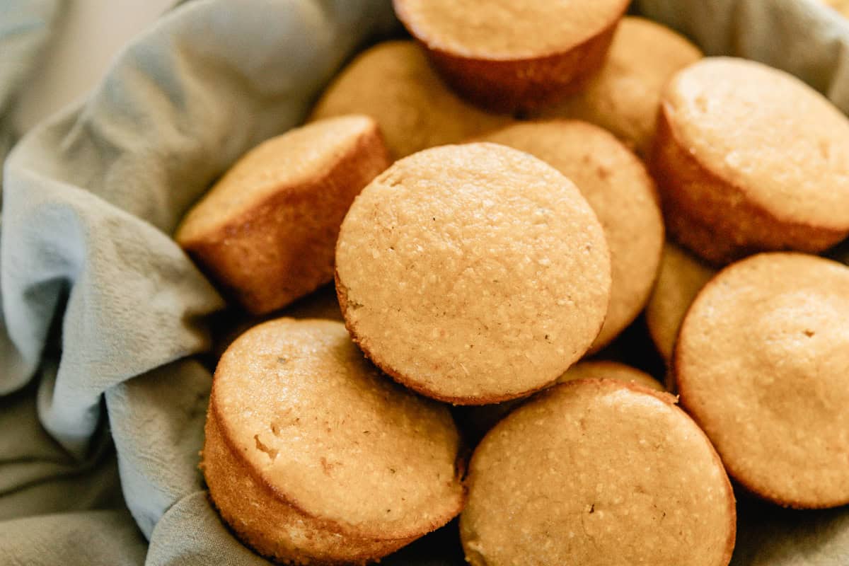 A stack of sweet corn muffins on a blue linen.