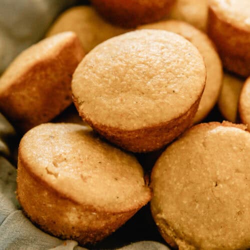 A basket of sweet corn muffins lined with a blue linen.
