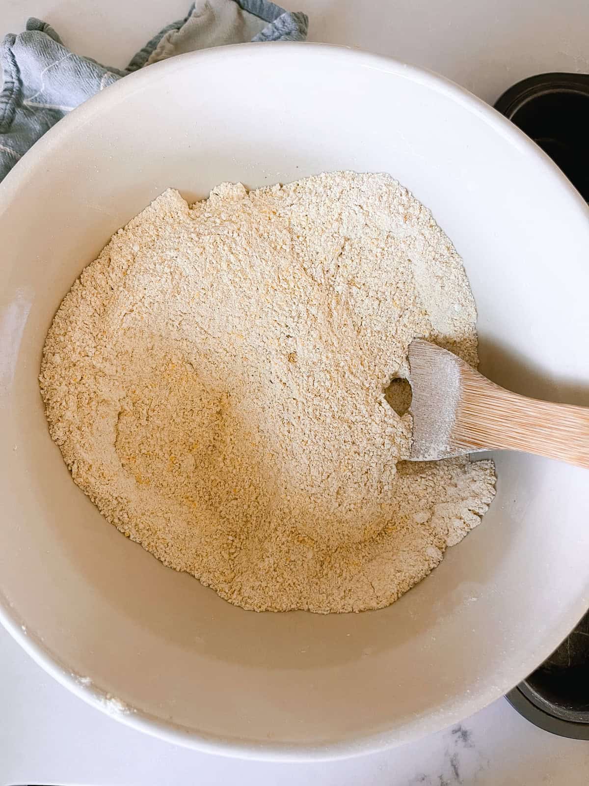 Stirring dry ingredients in a bowl with a wooden spoon.