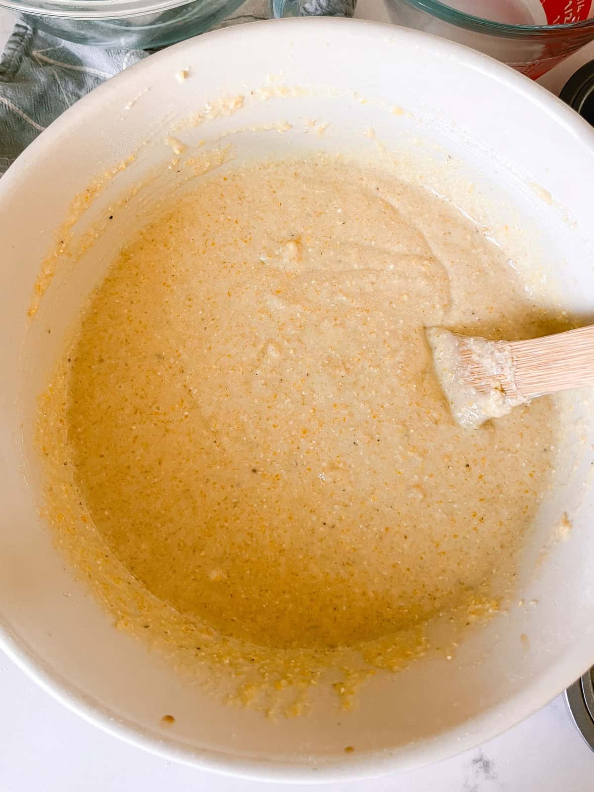 Sweet corn muffin batter in a mixing bowl with a wooden spoon.