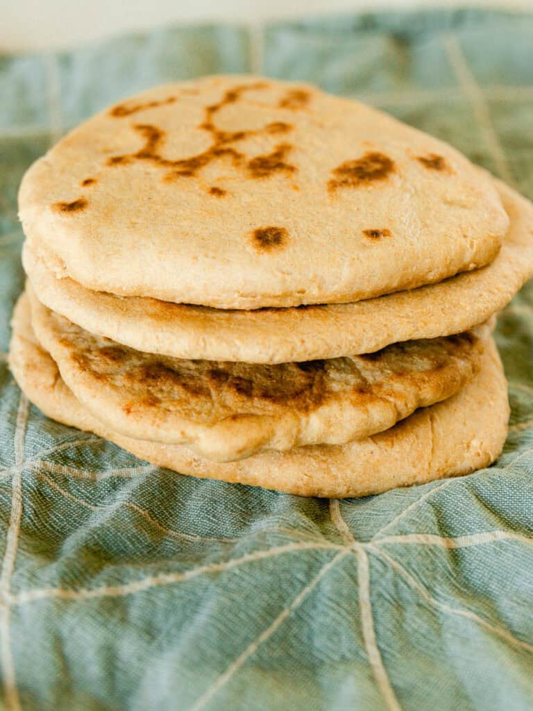 A stack of freshly milled flatbreads on a blue towel.