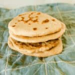 A stack of freshly milled flatbreads sitting on a blue towel.