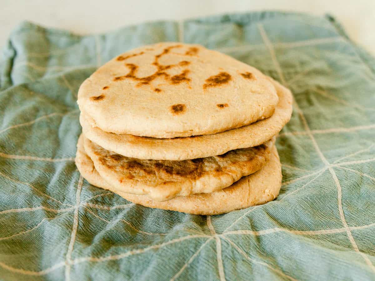 A stack of freshly milled flatbreads sitting on a blue towel.