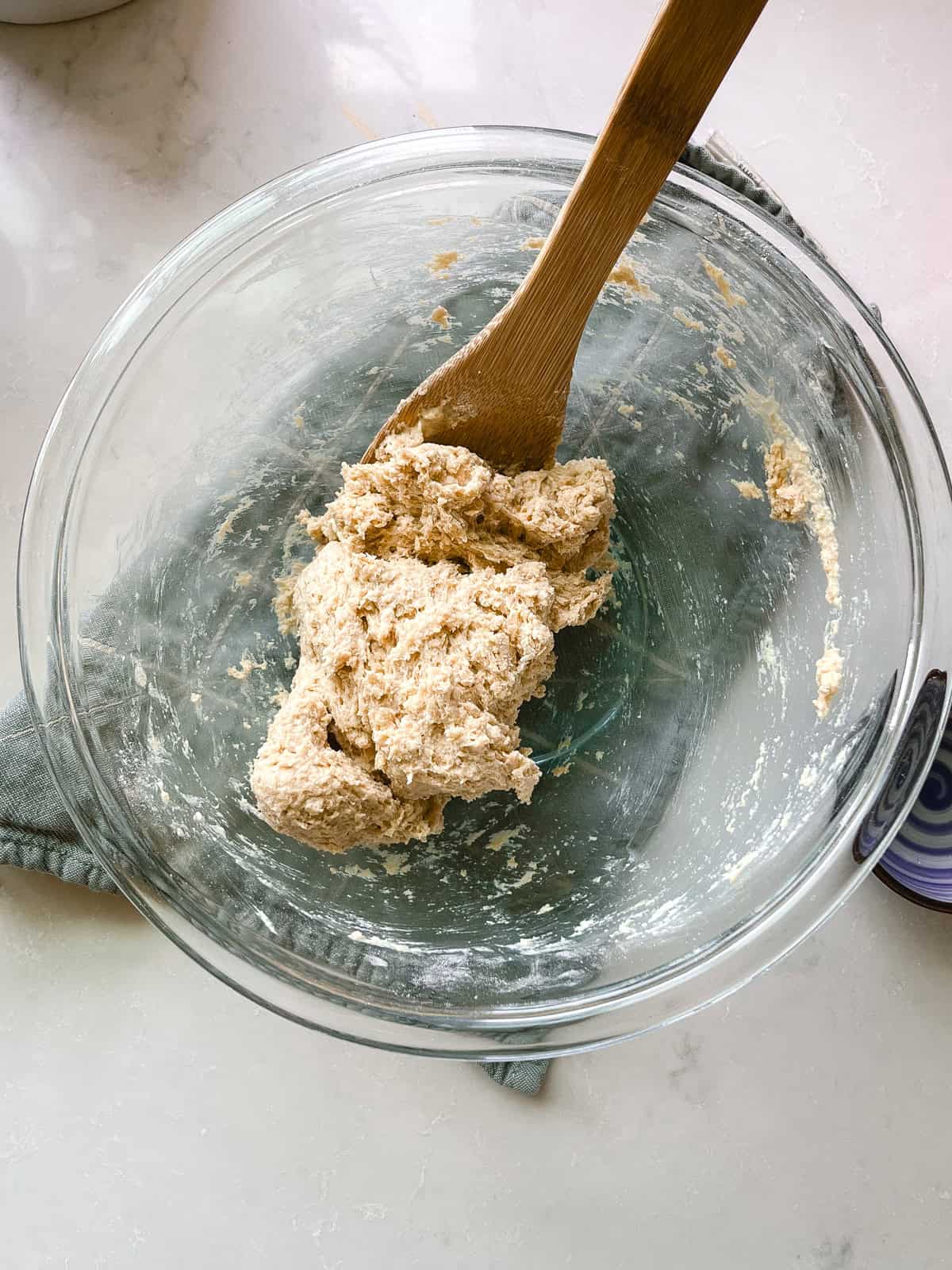 Shaggy dough formed into a ball in a glass mixing bowl.