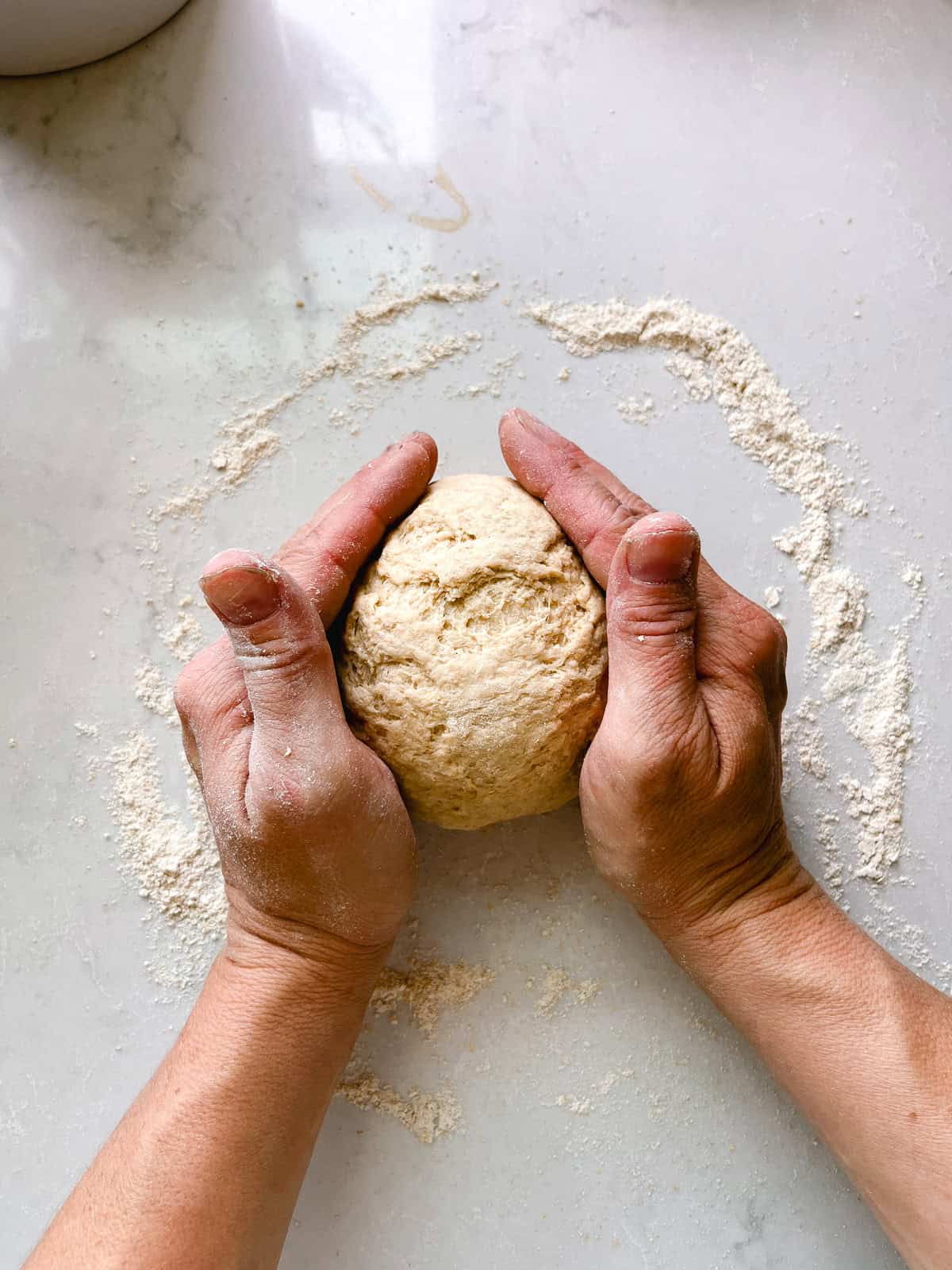 Kneading a ball of dough on a floured counter.