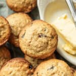 A pile of whole wheat oatmeal raisin muffins with butter on the side.