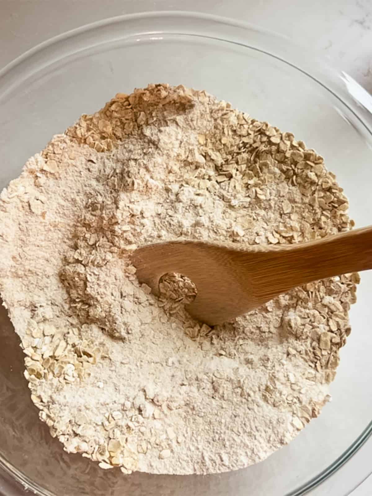 Stirring dry ingredients in a bowl with a wooden spoon.