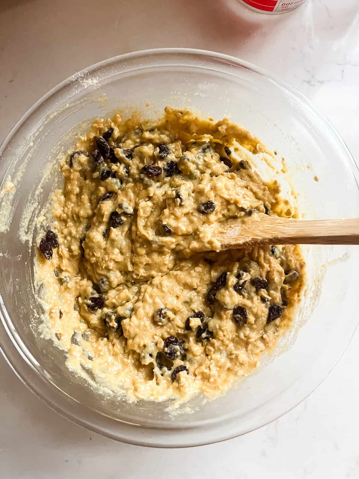 Stirring raisins into whole wheat oatmeal raisin muffin batter.