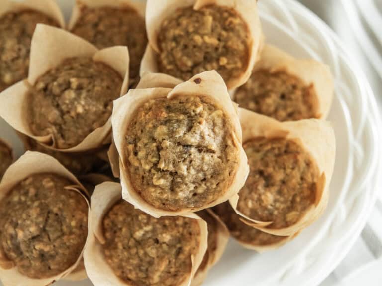 A white plate stacked high with banana oat muffins.
