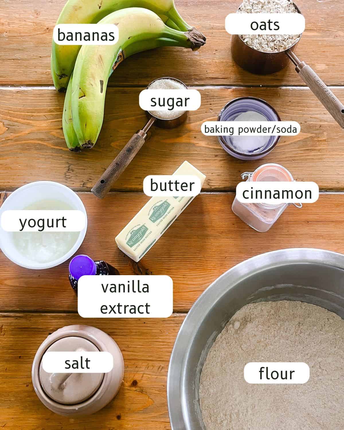 Banana oat muffin ingredients labeled on a wooden table.