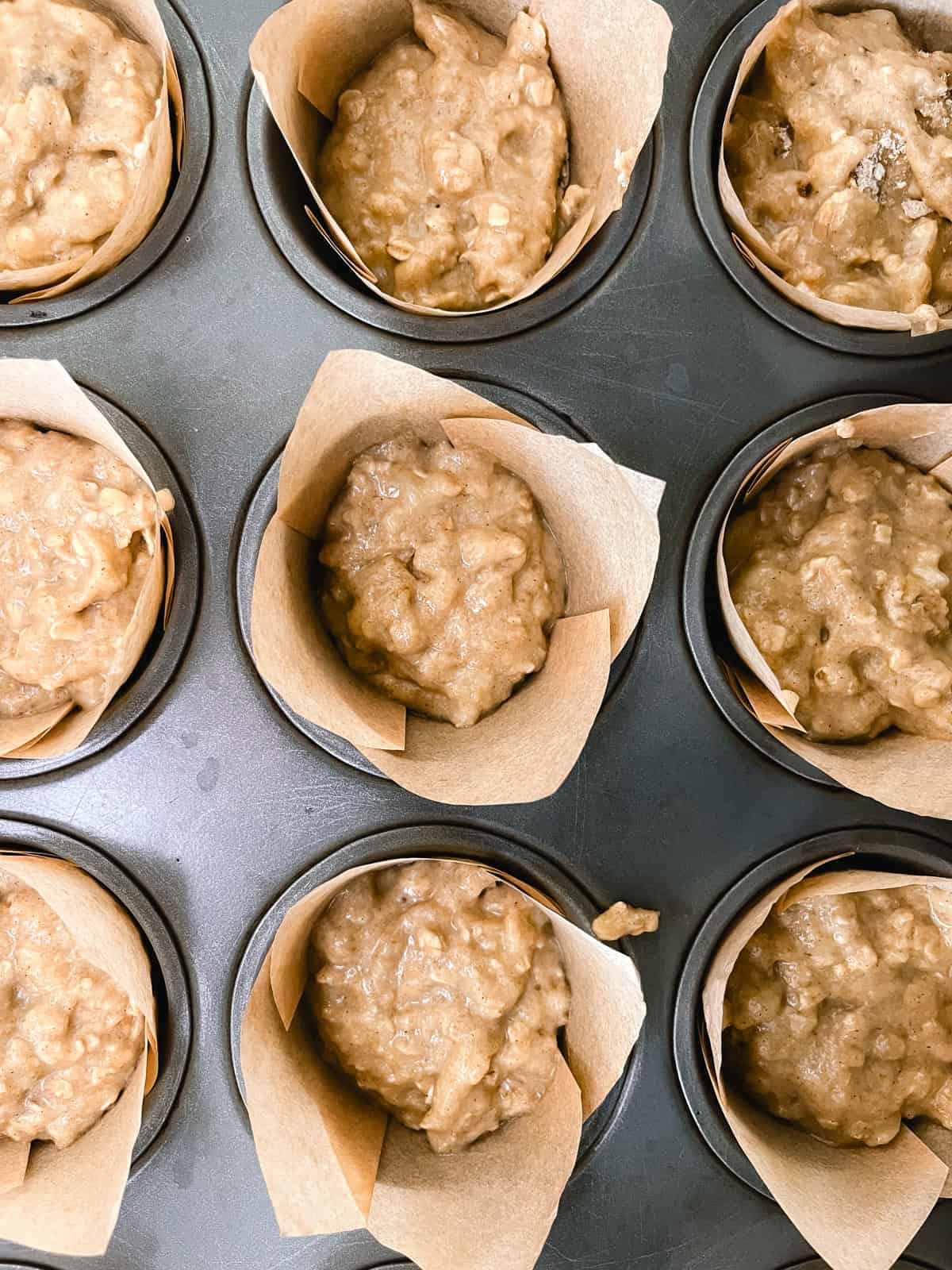 Raw banana oat muffin batter divided into paper-lined muffin tins.