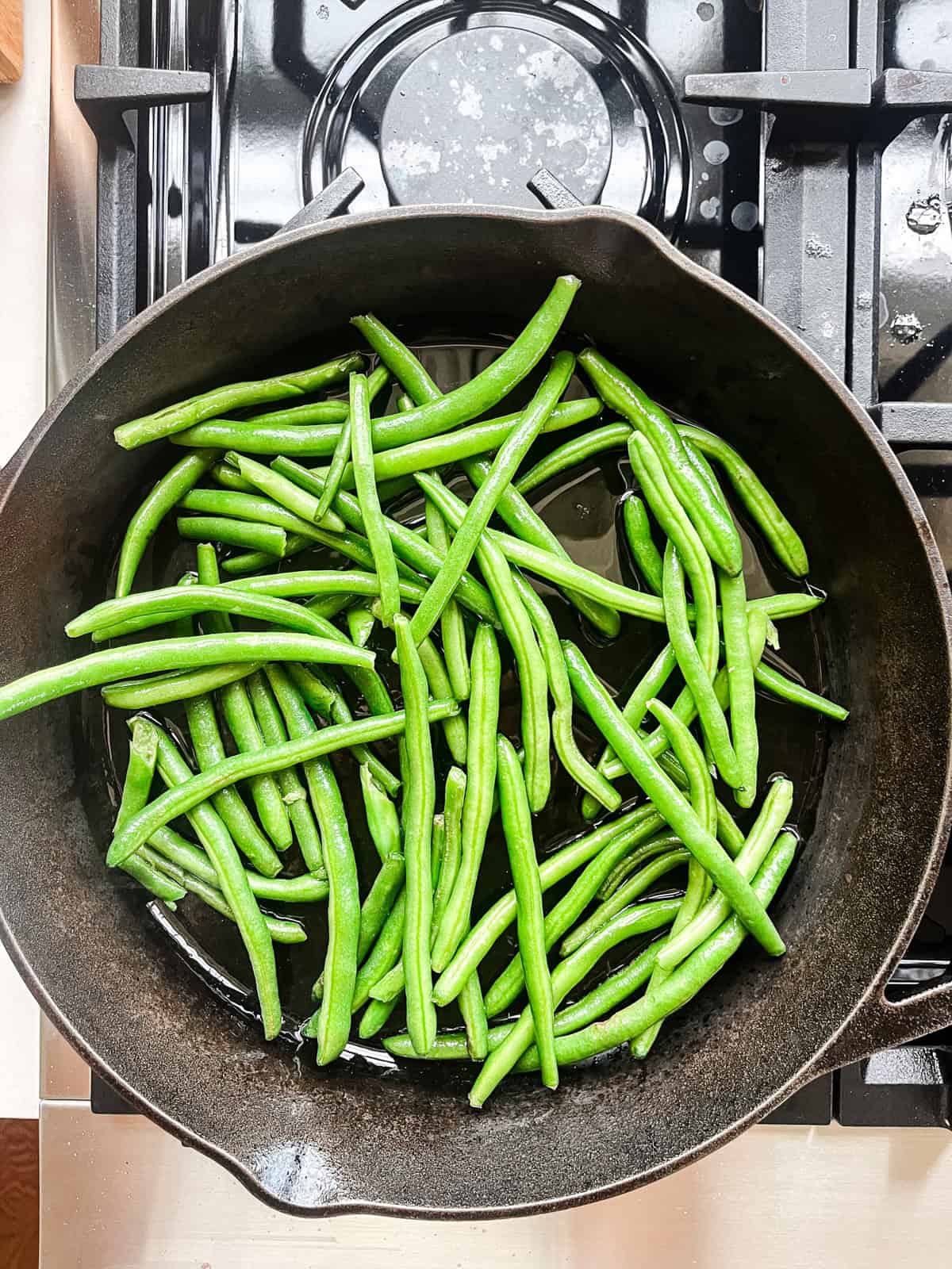 Fresh green beans cooking in a cast iron skillet.