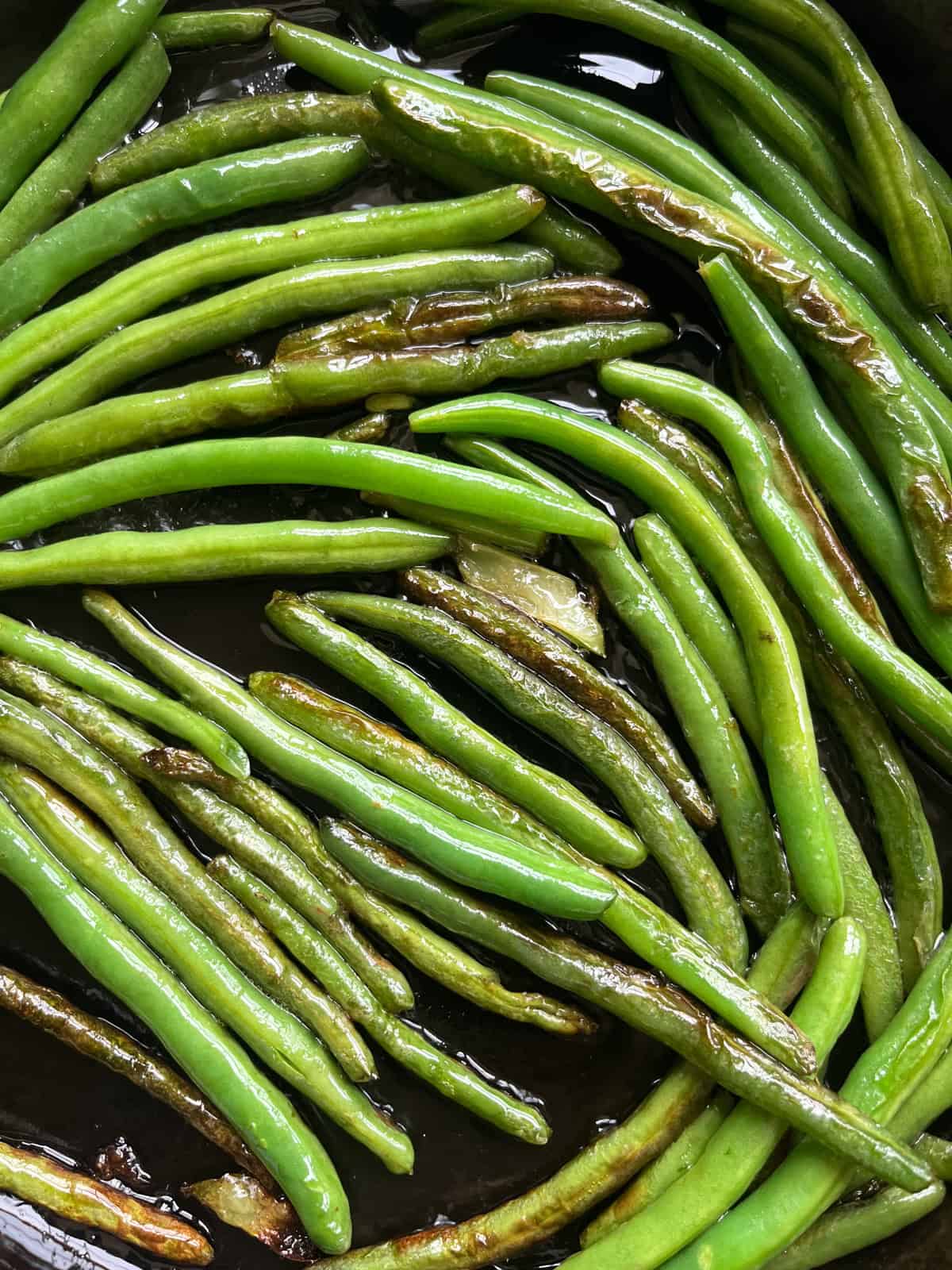 Green beans with a nice char on them in a cast iron skillet.