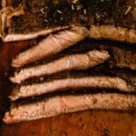 Sliced cast iron sirloin steak on a wooden cutting board.