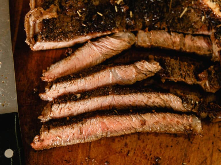 Sliced cast iron sirloin steak on a wooden cutting board.