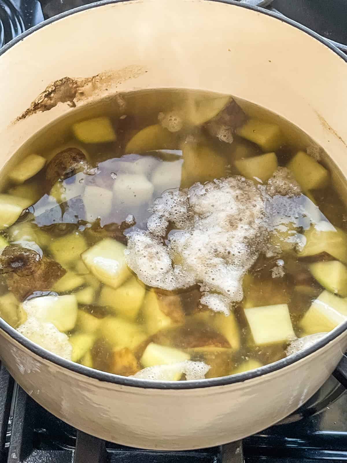 Boiling cubed potatoes in a dutch oven of water.