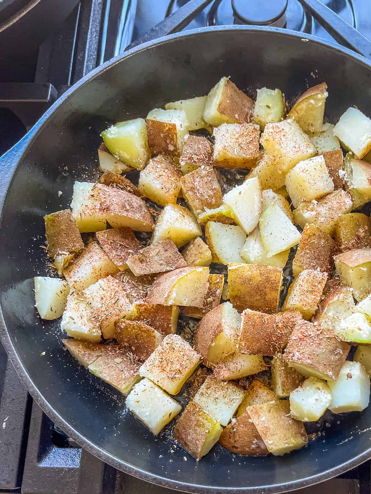 Boiled potatoes frying in a cast iron skillet.