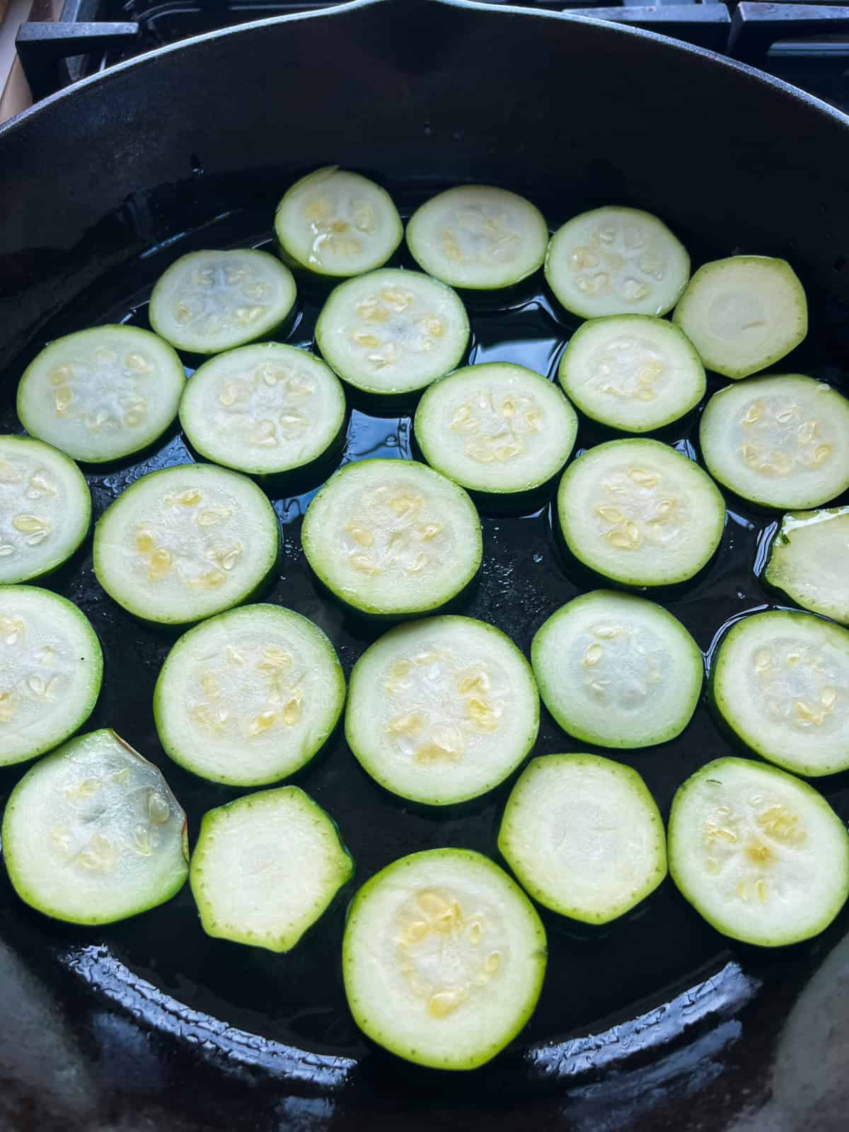 Sliced zucchini in a cast iron skillet.