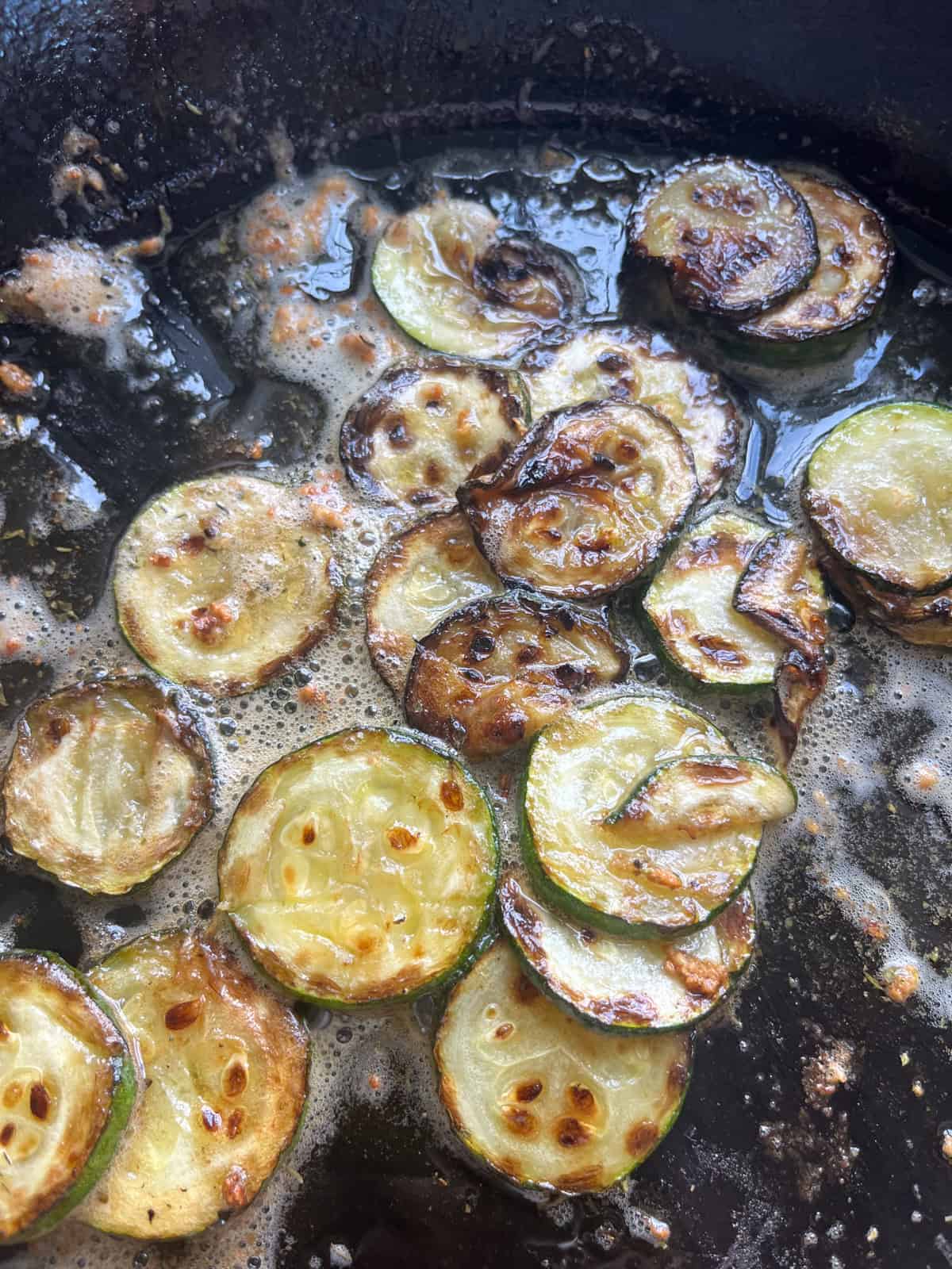Cooked zucchini in a cast iron skllet with melted butter.