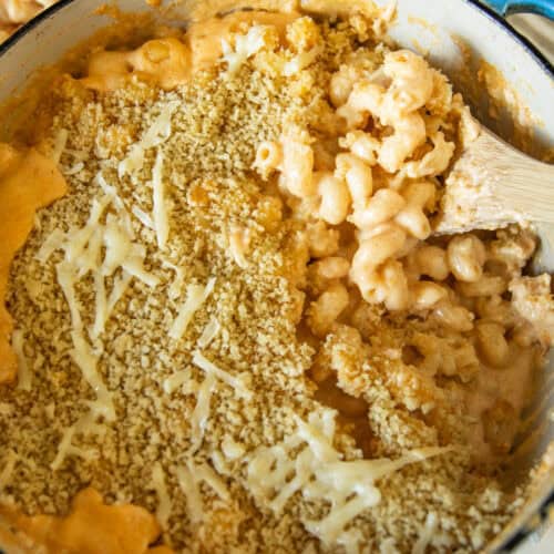 Scooping Dutch oven mac and cheese with a wooden spoon.