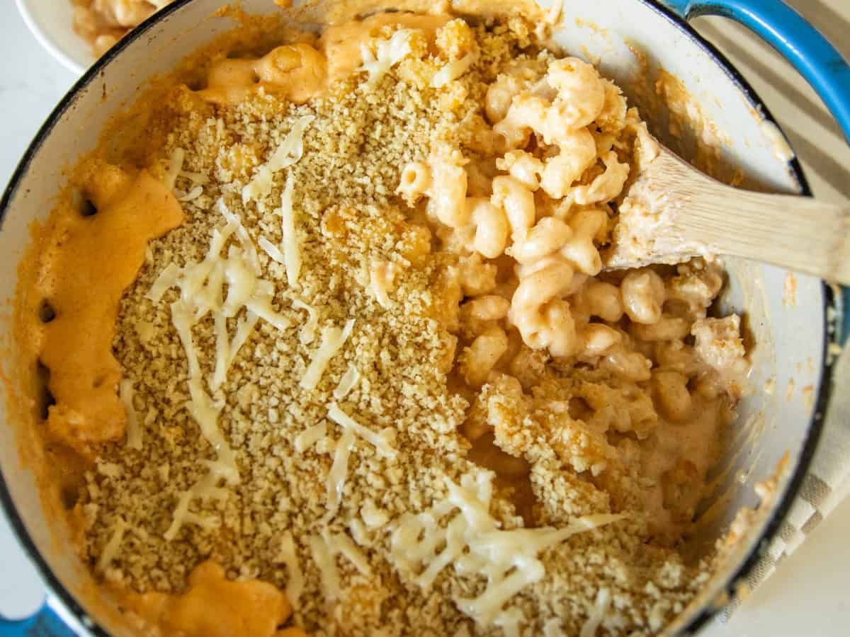 Scooping Dutch oven mac and cheese with a wooden spoon.