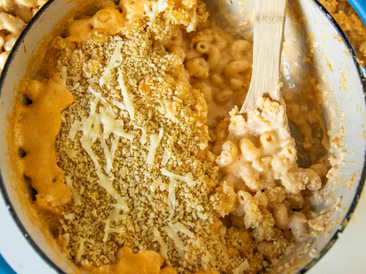 Serving Dutch oven mac and cheese with a wooden spoon.